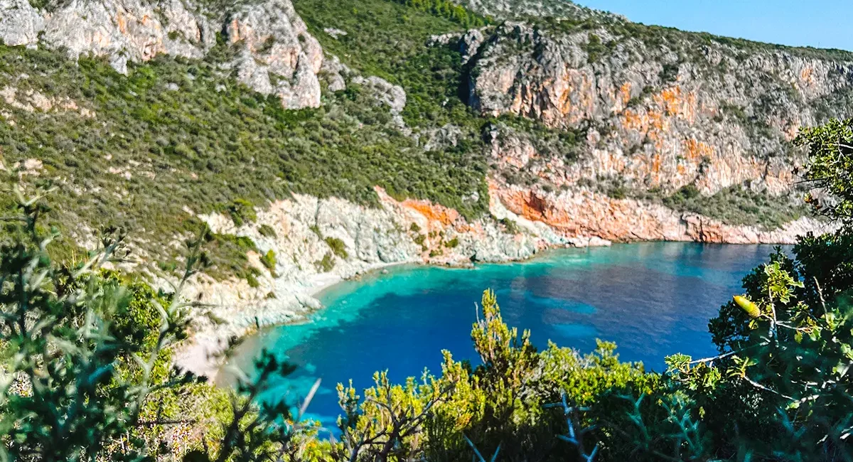 Ausblick auf eine türkisblaue Bucht während einer Wanderung überhalb des Meers