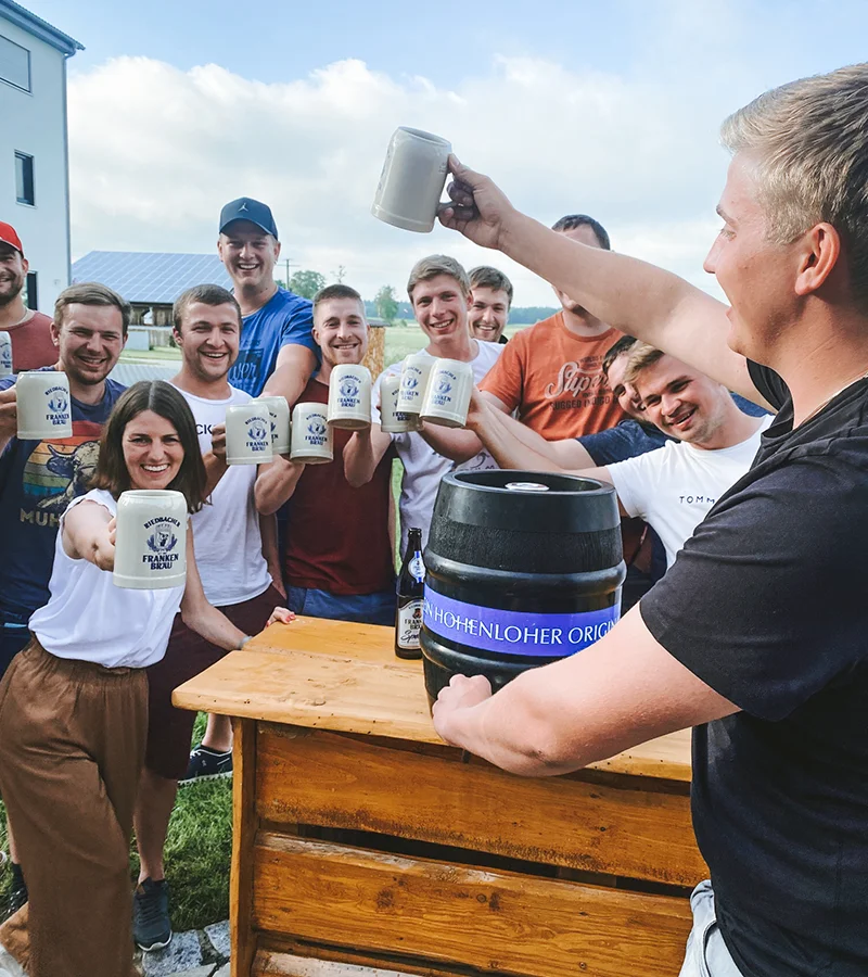 Eine junge Reisegruppe zu Besuch bei uns in Windisch-Bockenfeld. Alle halten Bierkrüge hoch.