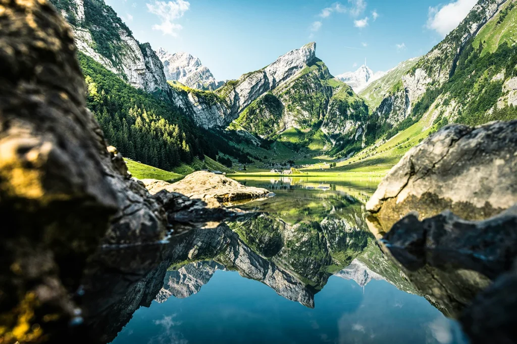 Der klare Seealpsee in der Schweiz, dessen Oberfläche die umliegenden Berge und den Himmel perfekt widerspiegelt.