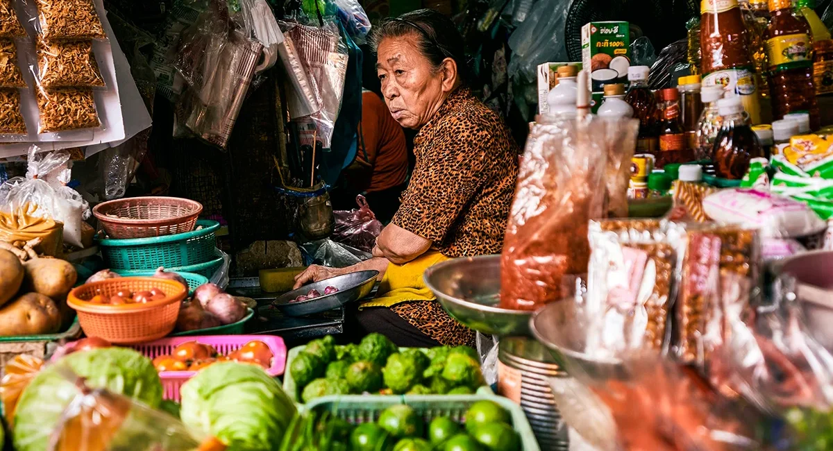 Eine thailändische Marktfrau an ihrem üppigen Marktstand in Bangkok.