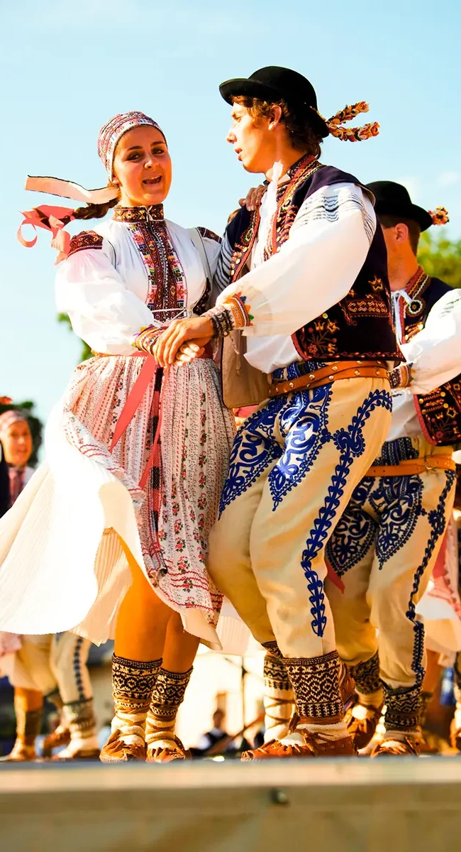 Eine Tanzgruppe führt in traditionell bestickten Gewändern einen tschechischen Folkloretanz auf.
