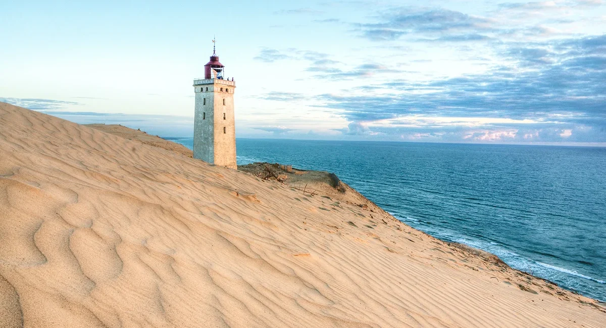 Der berühmte Rubjerg Knude Fyr Leuchtturm, der von einer massiven Wanderdüne und dem Meer an der Küste Dänemarks umgeben ist.