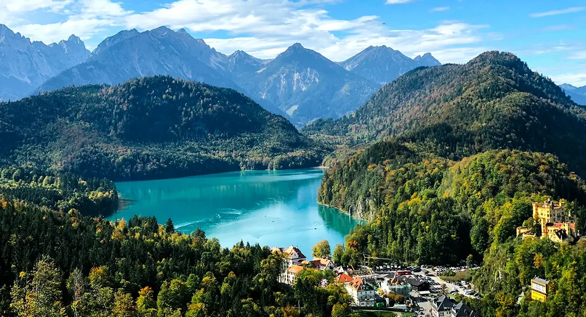 Der türkise Alpsee in Deutschland liegt nahe den Schlössern Neuschwanstein und Hohenschwangau, umgeben von Wäldern und Bergen.
