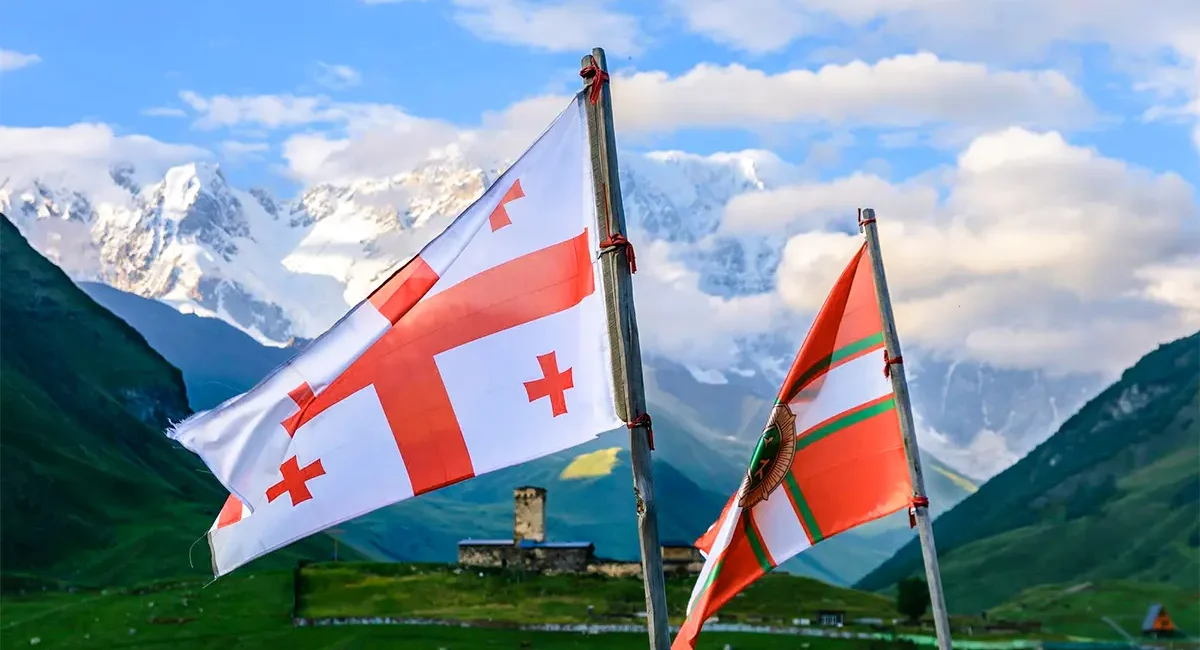 Die Flagge Georgiens weht vor dem beeindruckenden Bergpanorama