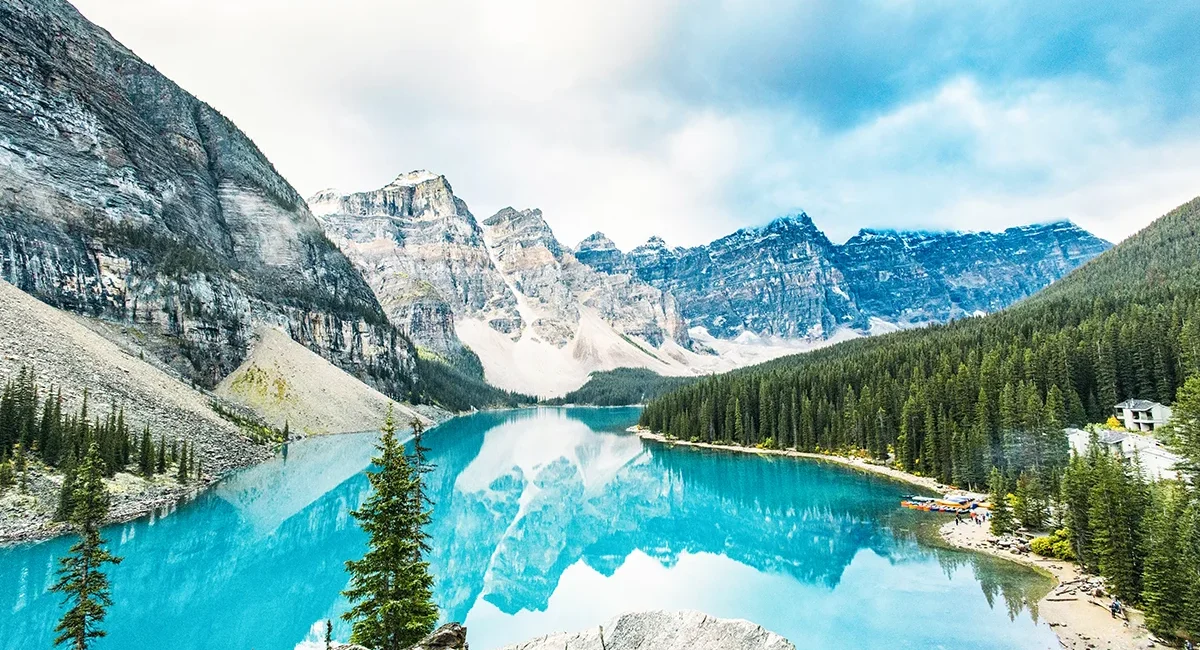 Der Moraine Lake, einen leuchtend türkisfarbenen Gletschersee umgeben von Nadelwäldern und den imposanten, schneebedeckten Gipfeln der Kanadischen Rocky Mountains im Banff-Nationalpark in Kanada.