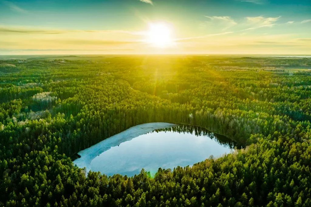 Ein malerischer See, umgeben von einem dichten Wald, bei Sonnenuntergang in Lettland.
