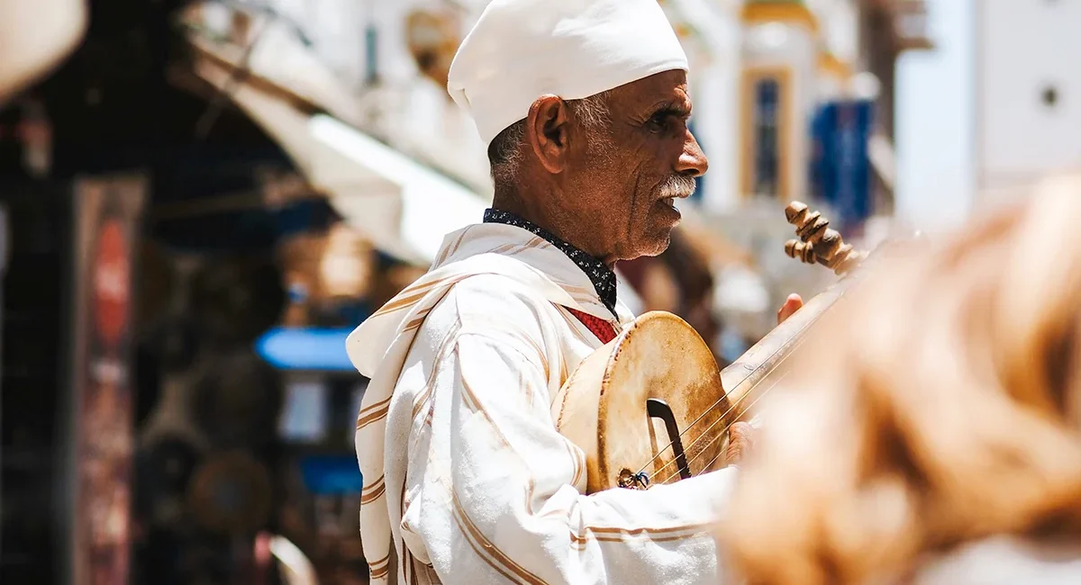 Ein einheimischer Musiker spielt ein traditionelles Instrument auf einer Straße in Marokko.