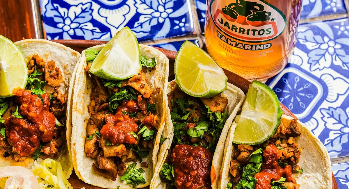 Ein Teller mit gefüllten mexikansichen Tacos und einem typischen Getränk.