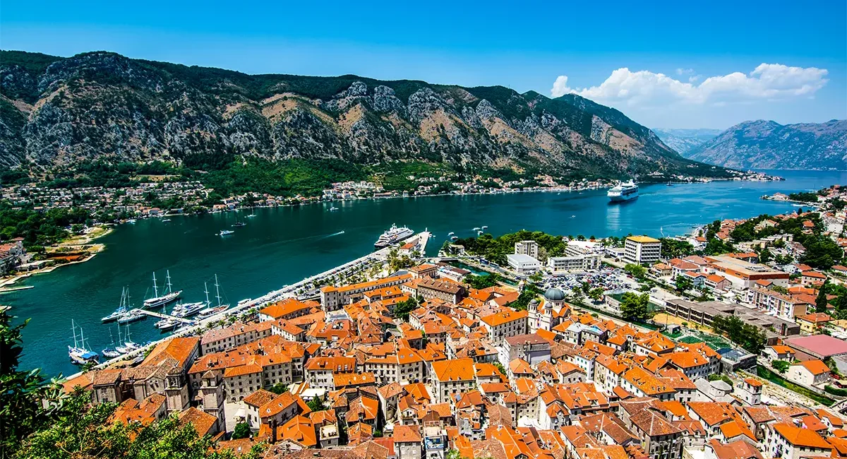 Eine Panoramaansicht der historischen Altstadt von Kotor in Montenegro, gelegen an der tiefblauen Bucht von Kotor und umgeben von hoch aufragenden Bergen.