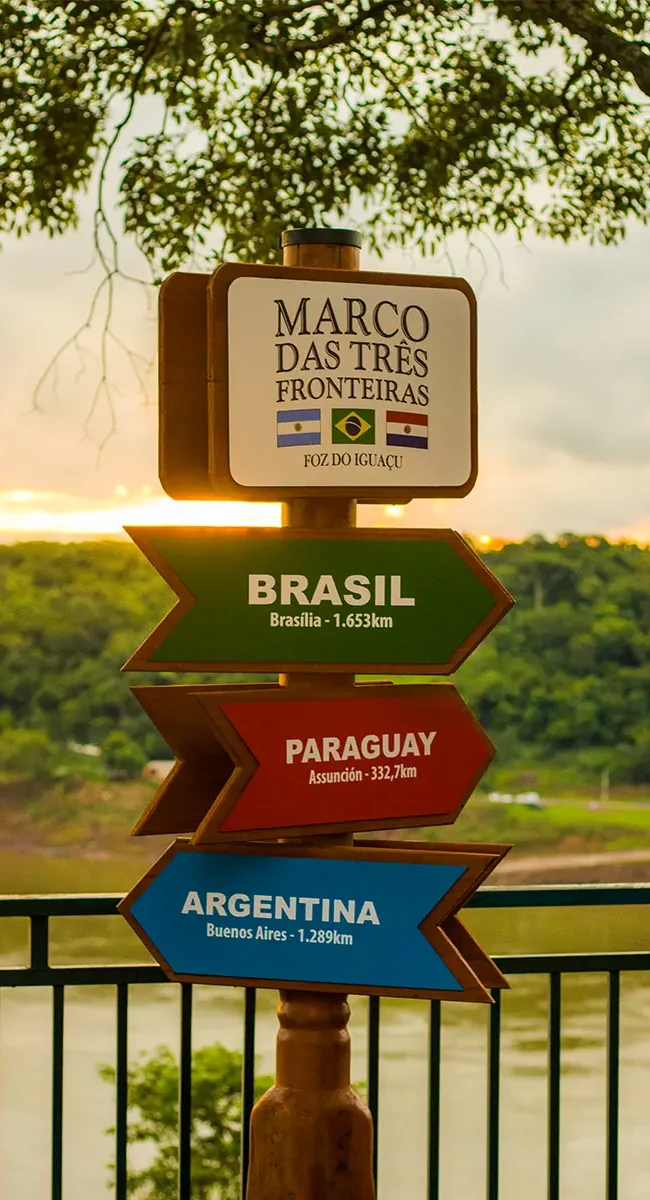 Ein Wegweiser am Dreiländereck zeigt mit farbigen Pfeilschildern in die Richtungen von Brasilien, Paraguay und Argentinien.