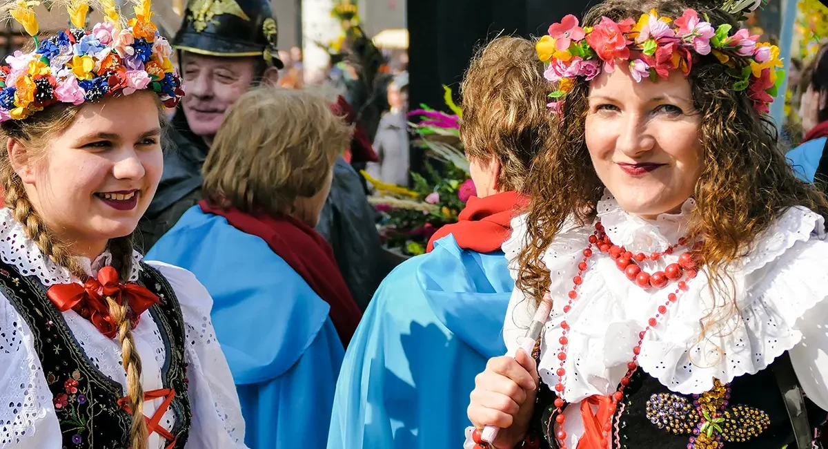 Zwei Frauen in traditioneller polnischer Tracht und Blumenkränzen auf den Köpfen.