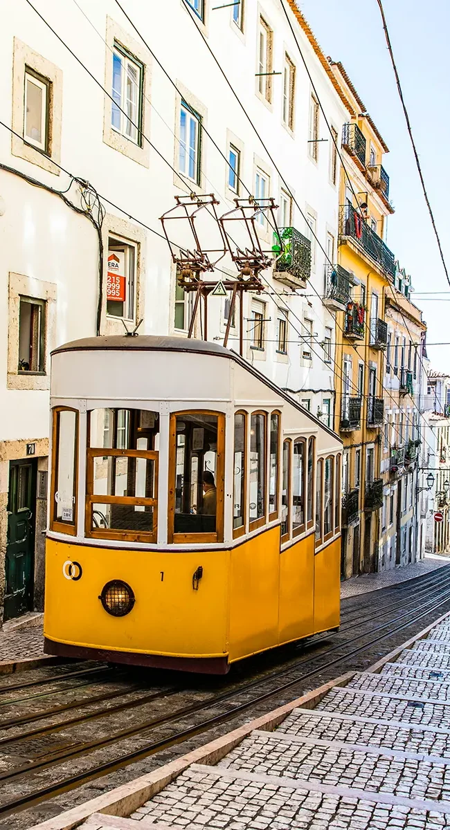 Die historische gelbe Straßenbahn fährt durch die engen steilen Gassen von Lissabon in Portugal.