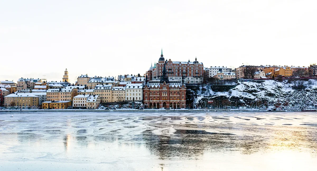 Die historische Skyline von Stockholm im Winter bei Schnee und gefrorenen Gewässern im Vordergrund.