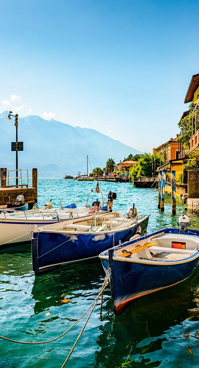 Kleine Fischerboote liegen am Hafen des Ortes Limone sul Garda am Gardasee in Italien.