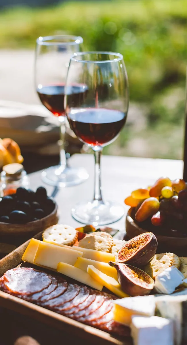 Zwei Gläser Wein auf einem Tisch mit Wurst, Käse und Früchten auf Korsika.