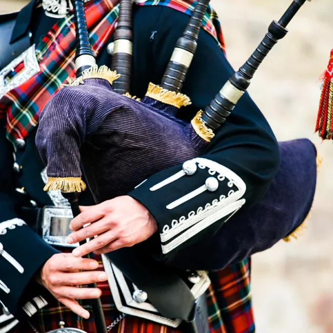 Ein Dudelsackspieler in traditioneller schottischer Kleidung und schottischen Dudelsack.