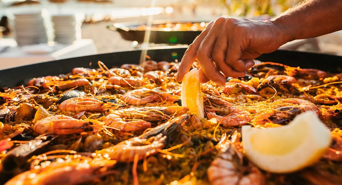 Eine Pfanne mit Paella aus Spanien, zubereitet mit Reis und verschiedenen Zutaten wie Meeresfrüchten.