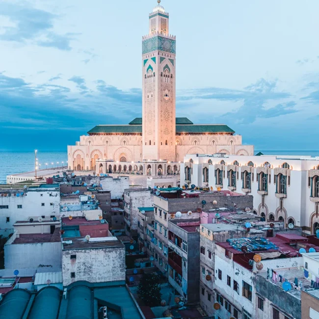 Die Hassan-II.-Moschee in Casablanca steht direkt an der Atlantikküste Marokkos. Das große Minarett und die weitläufige Moschee ragen über das Meer und die Stadt hinaus.