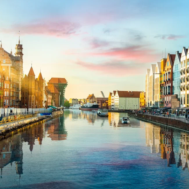 Die Altstadt von Danzig mit historischen Häusern am Hafen entlang der Mottlau. Bunte Fassaden spiegeln sich im Wasser des Hafens.