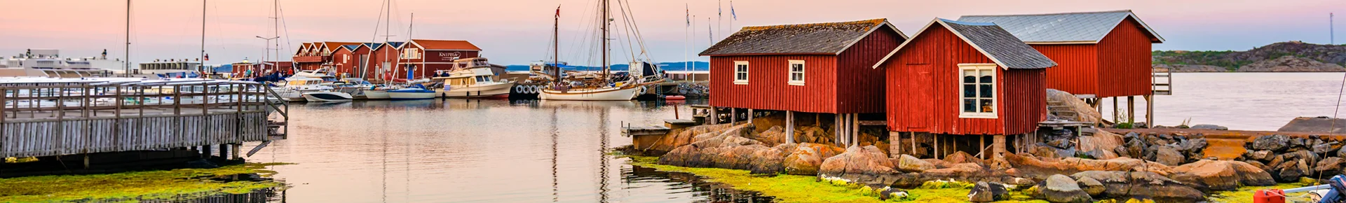 Panoramablick auf einen kleinen Bootshafen in Göteborg in Schweden. Mehrere Boote liegen am Steg, im Hintergrund stehen rote Gebäude am Ufer.