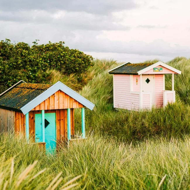 Zwei bunte Strandhütten stehen nebeneinander am Strand von Skanör in Schweden.