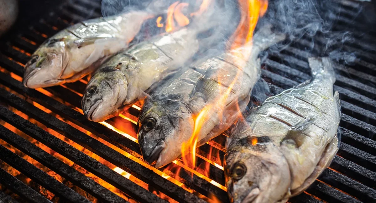 Mehrere Fische werden in Bulgarien auf einem Grill über offenem Feuer zubereitet.
