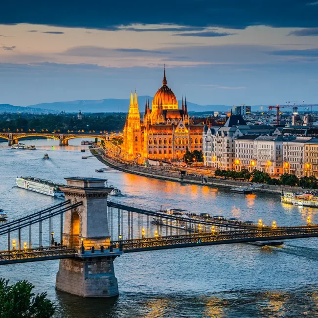 Budapest in der Abendstimmung mit beleuchteten Brücken über der Donau und dem hell erleuchteten Parlament.