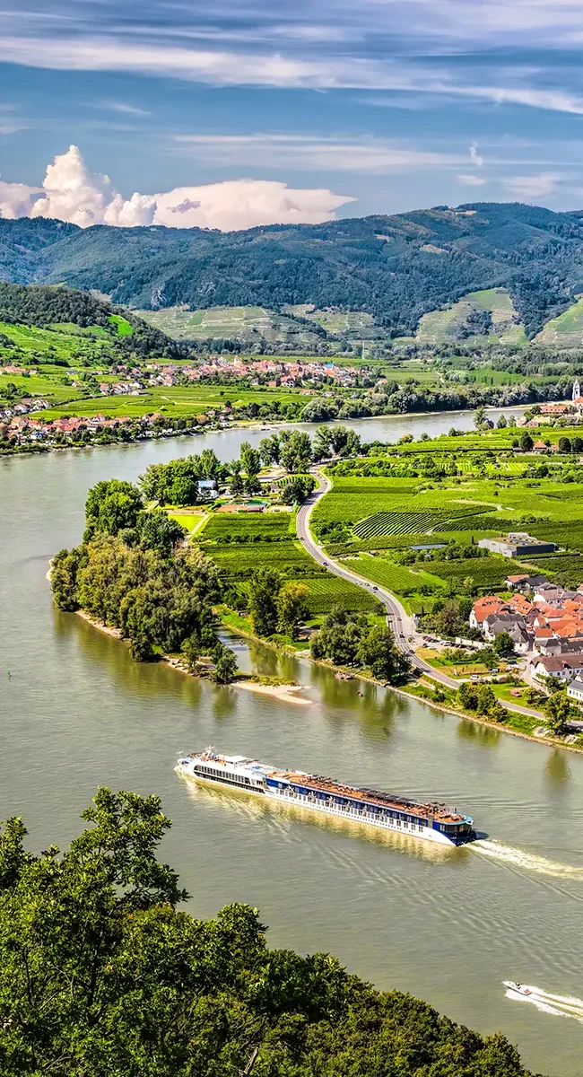 Blick auf die Donau in der Wachau mit einem Flusskreuzfahrtschiff auf dem Wasser.