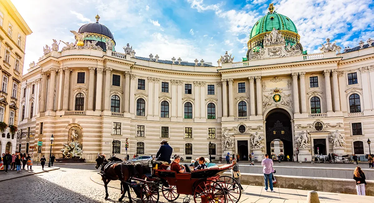Eine Kutschfahrt in Wien vor einem historischen Gebäude. Die Pferdekutsche fährt durch die Altstadt vor beeindruckender Architektur.