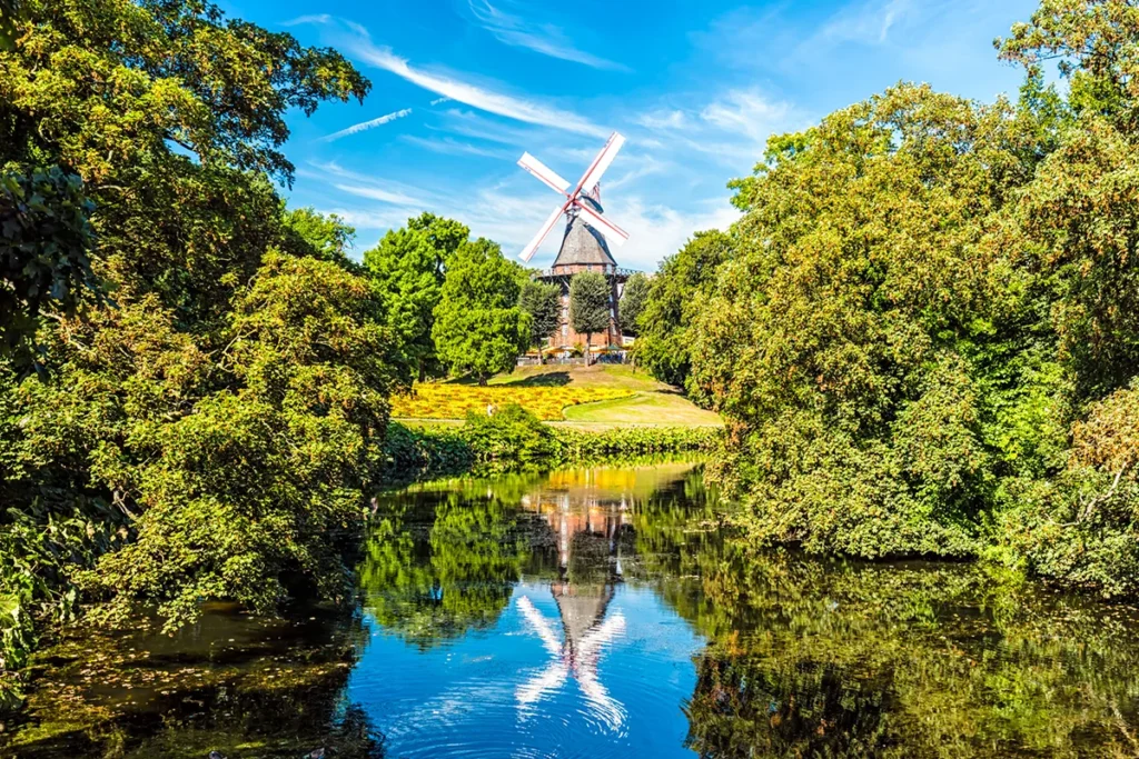 Die historische Mühle am Wall in Bremen, die sich idyllisch in den herbstlichen Wallanlagen am Ufer des Wallgrabens spiegelt.