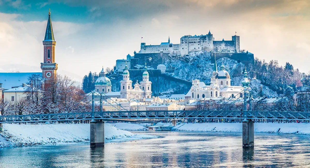 Die winterliche Kulisse Salzburgs mit Blick auf die schneebedeckte Festung Hohensalzburg und den Fluss Salzach in Österreich